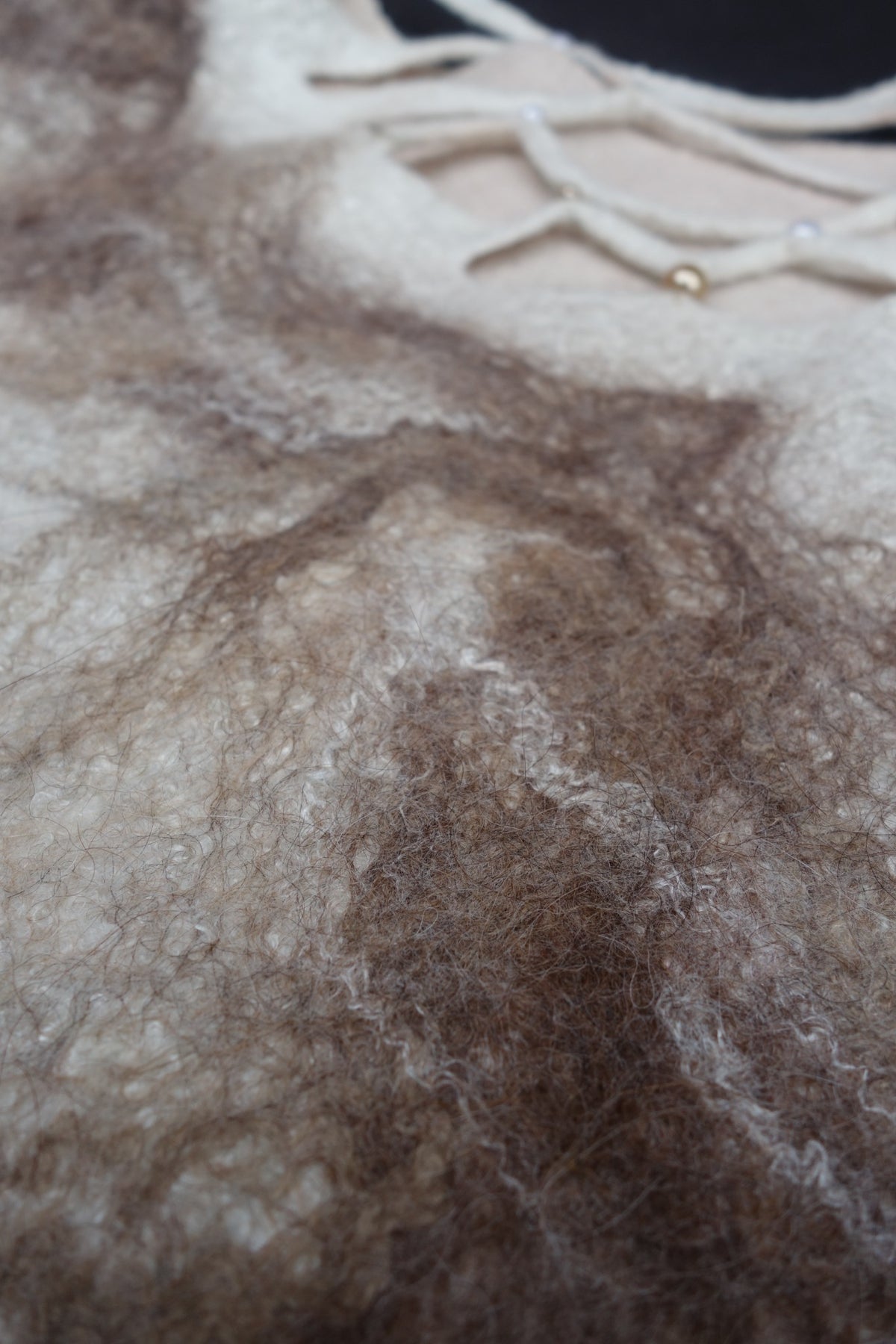 Close-up of taupe alpaca and fiber texture on ivory felted wool top