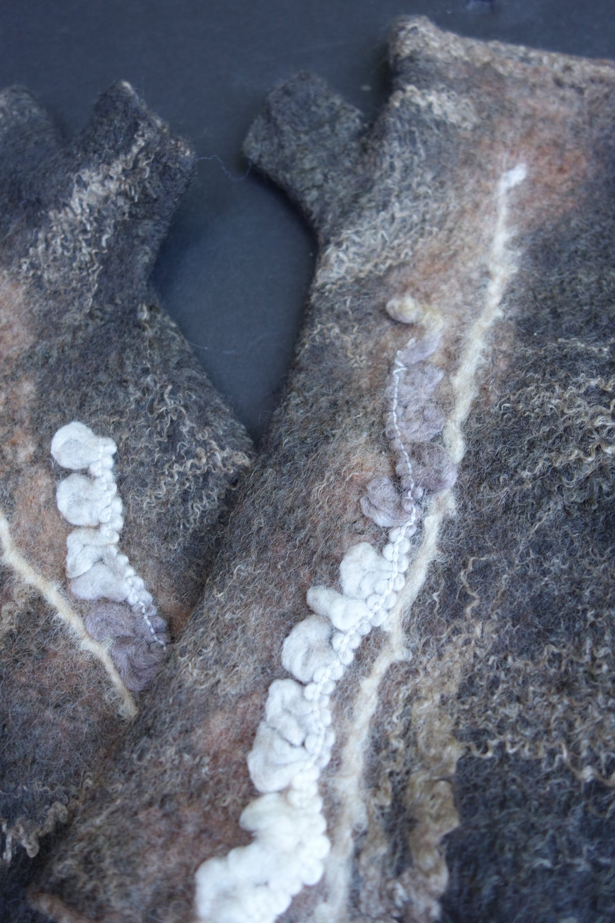Close-up of sculptural fiber detail on hand-felted fingerless gloves