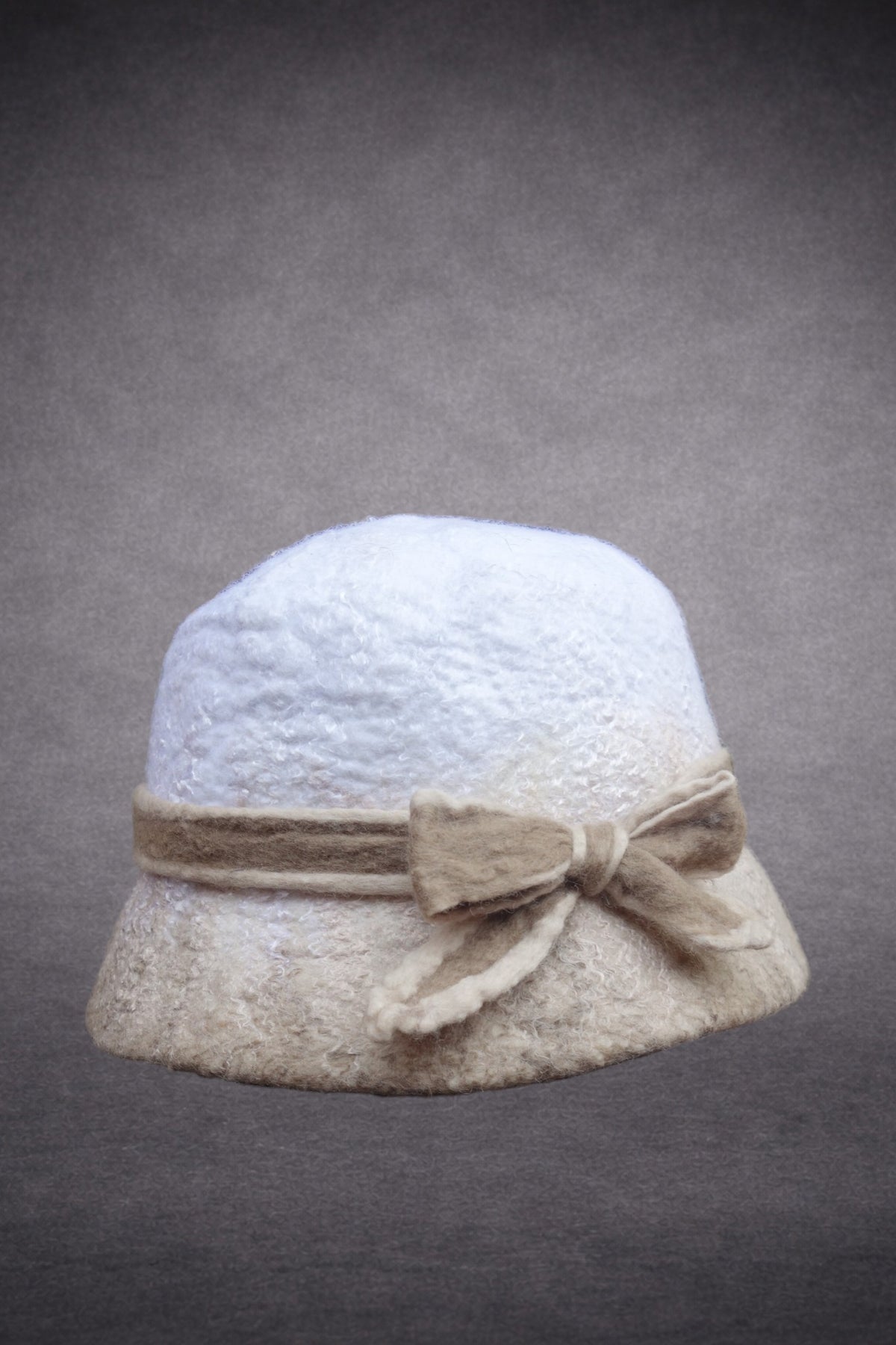 Side view of ivory and beige hand-felted bucket hat showing sculptural bow detail