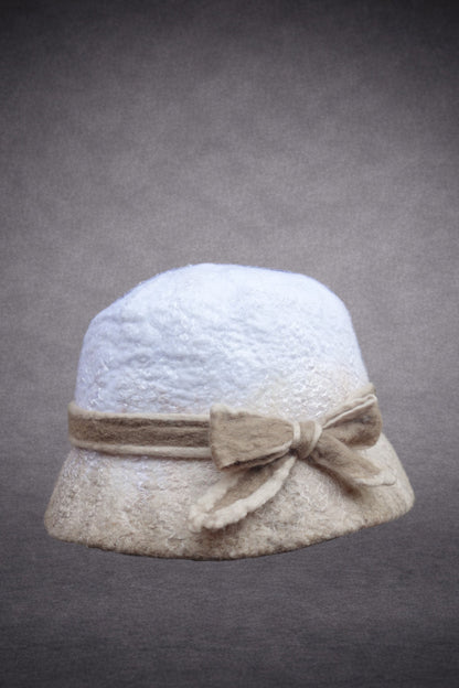 Side view of ivory and beige hand-felted bucket hat showing sculptural bow detail