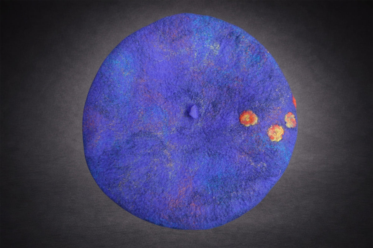 Top view of blue hand-felted beret with small orange and golden-yellow floral accents