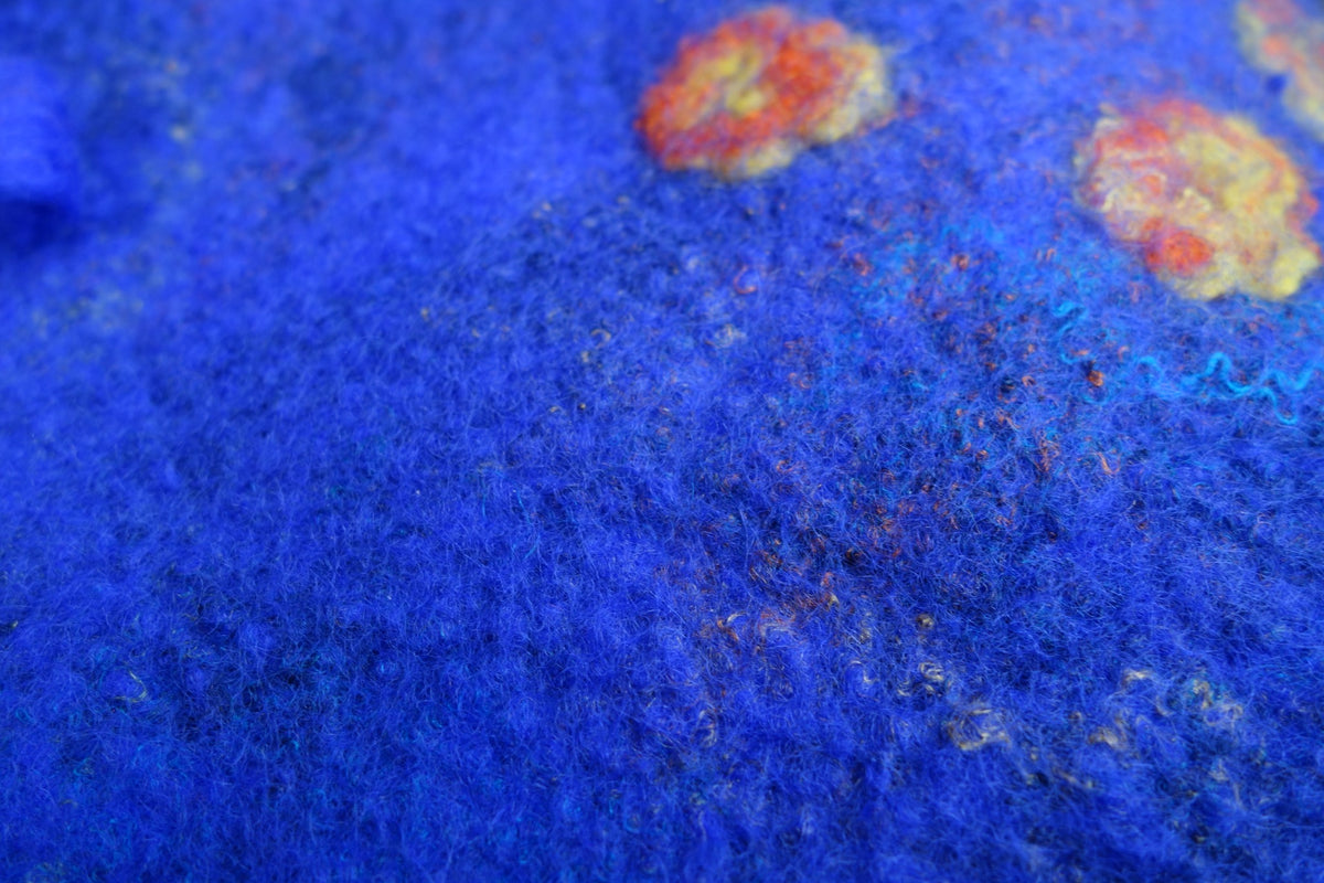 Close-up of blue felted beret texture with multicolor fibers and floral details
